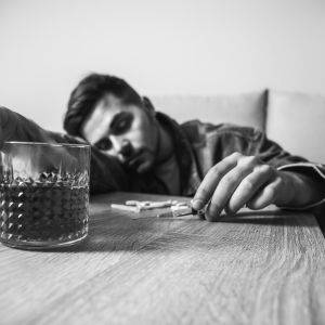 man suffering from addiction passed out with alcohol and pills.